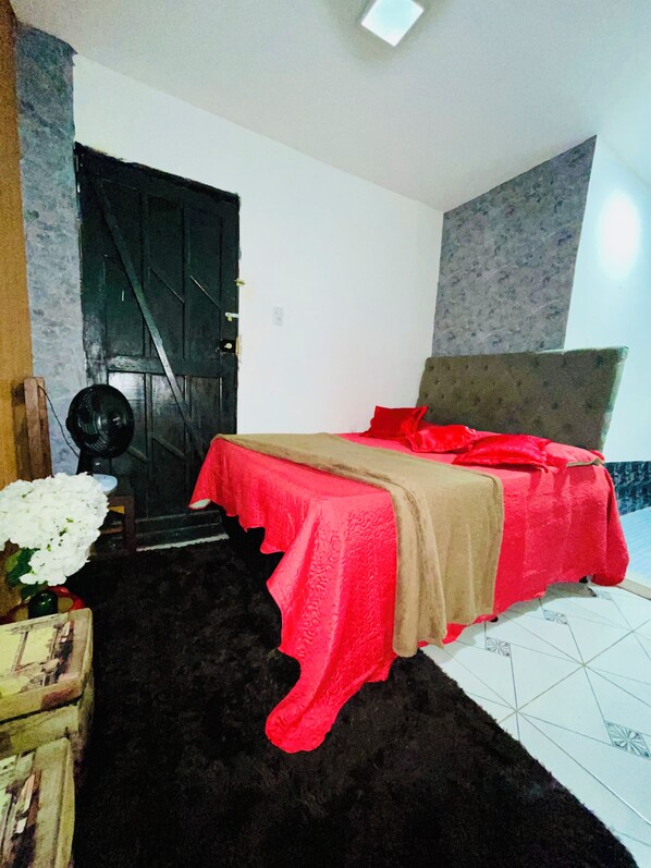 Un dormitorio con cama, puerta, ventilador y alfombra.