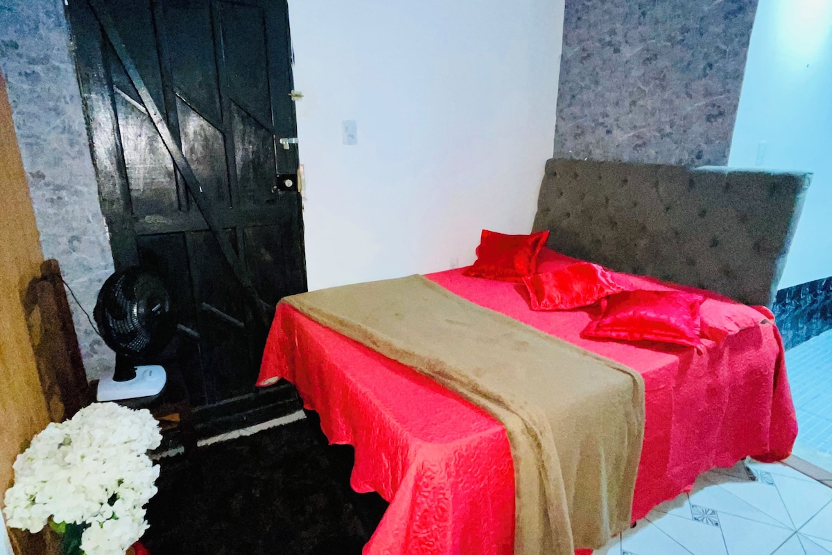 Een slaapkamer met een bed, een deur, een ventilator en een betegelde vloer.