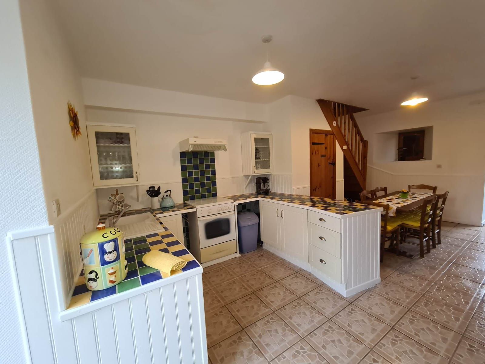 A compact kitchen with white cabinets, a central island, and a dining area with a table and chairs.