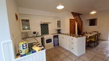 A compact kitchen with white cabinets, a central island, and a dining area with a table and chairs.