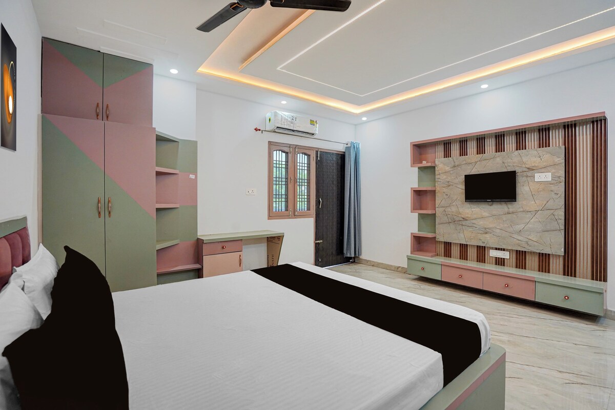 Un dormitorio con cama, armario, televisor montado en la pared y ventilador de techo.