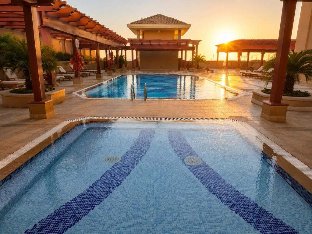 Une piscine dont le fond est recouvert de carreaux décoratifs, entourée de chaises longues et d’un espace abrité par un toit.