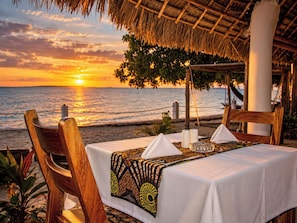A table set for two with a view of the ocean at sunset. - Zuri Sana Beach Hotel  (Zanzibar)