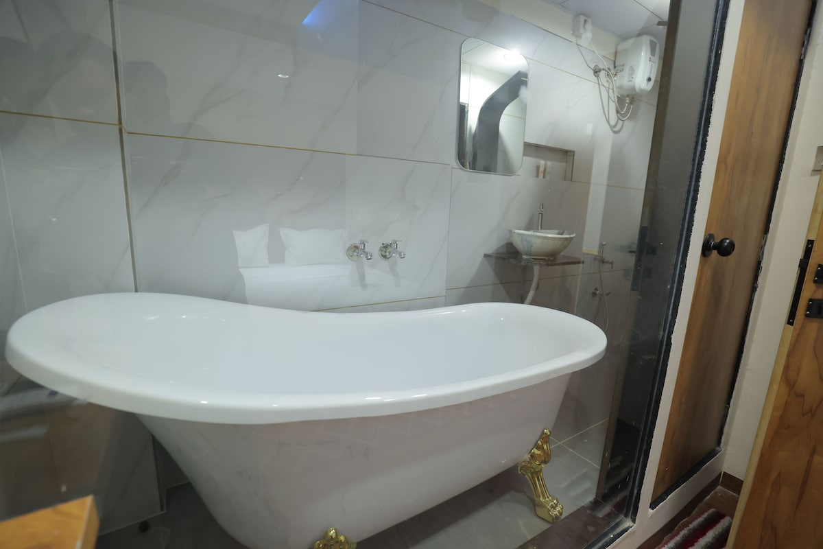Un bany amb banyera independent, dutxa amb envàs de vidre i un lavabo blanc.