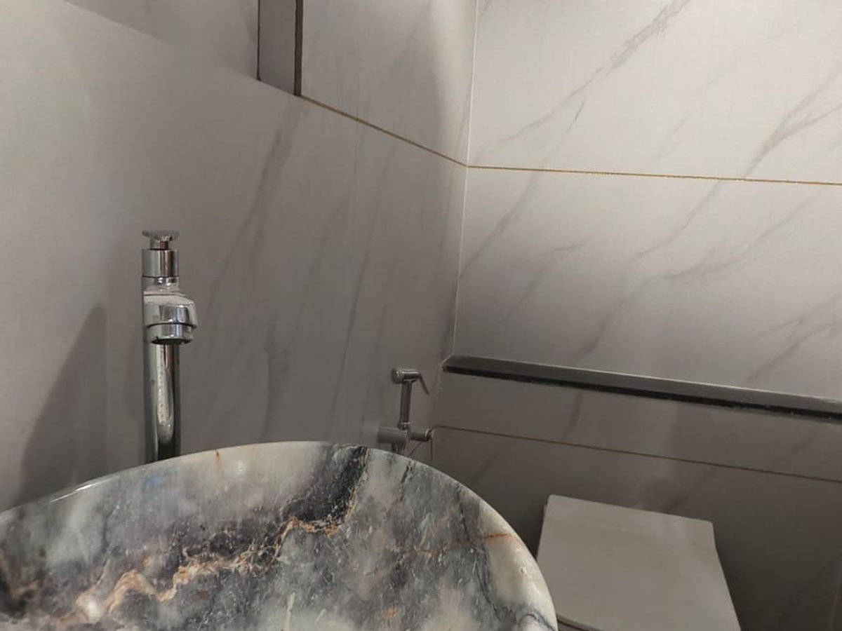 A bathroom with a marble sink, a faucet, and a toilet.