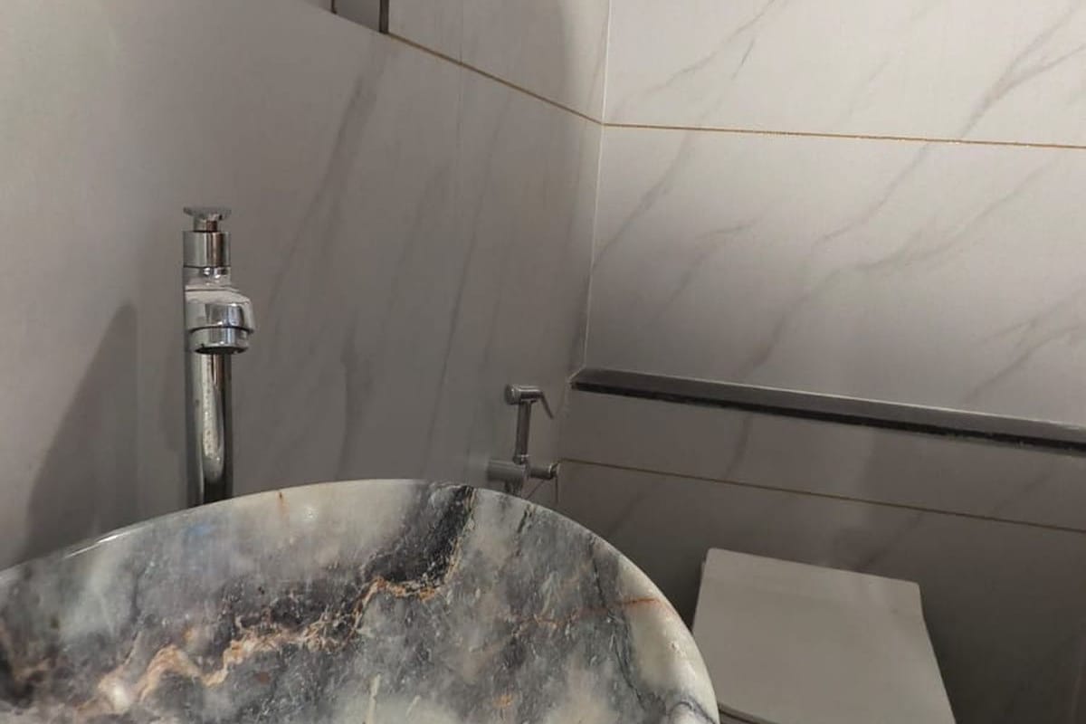 Un bany amb un lavabo de marbre, un aixeta i un vàter.