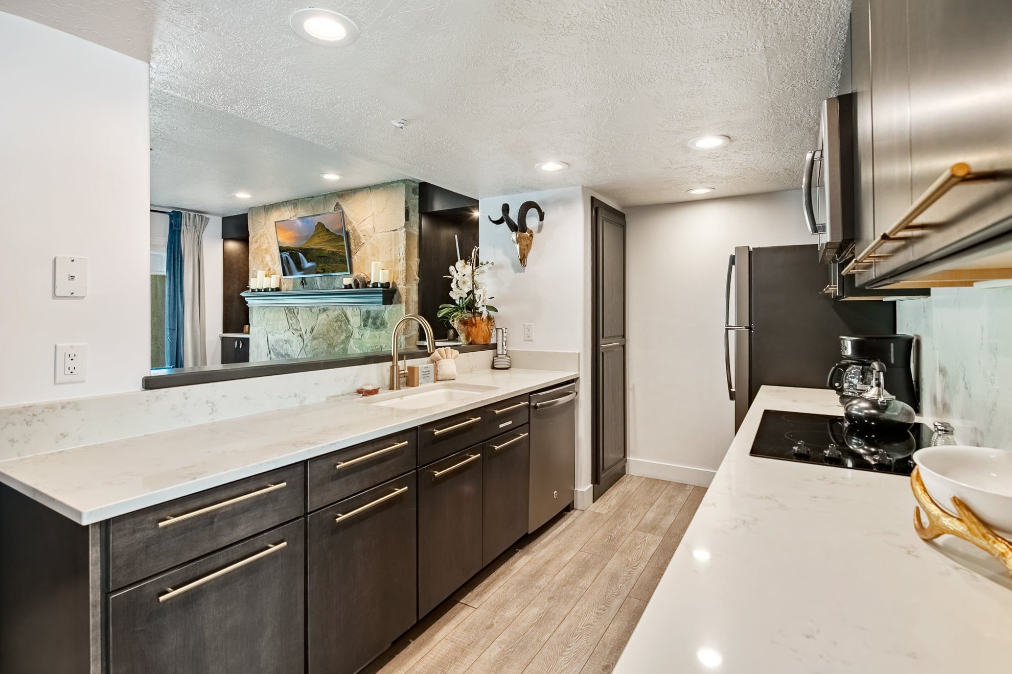 A modern kitchen with a marble countertop, stainless steel appliances, and a large mirror.