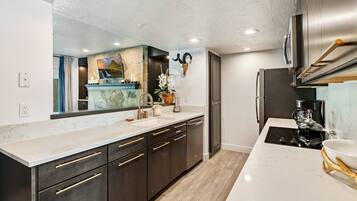 A modern kitchen with a marble countertop, stainless steel appliances, and a large mirror.