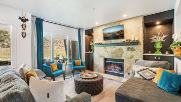 A spacious living room with a fireplace, comfortable seating, and a view of the outdoors.