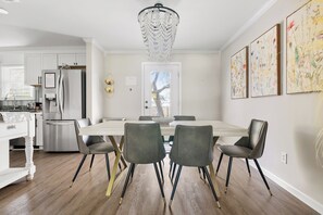 Et moderne køkken med et rustfrit stål køleskab, et spisebord med stole og en lysekrone.