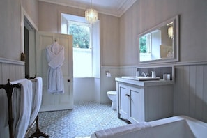 A bathroom with a white bathtub, a sink, a toilet, and a mirror. - Isla Bank House (Keith)
