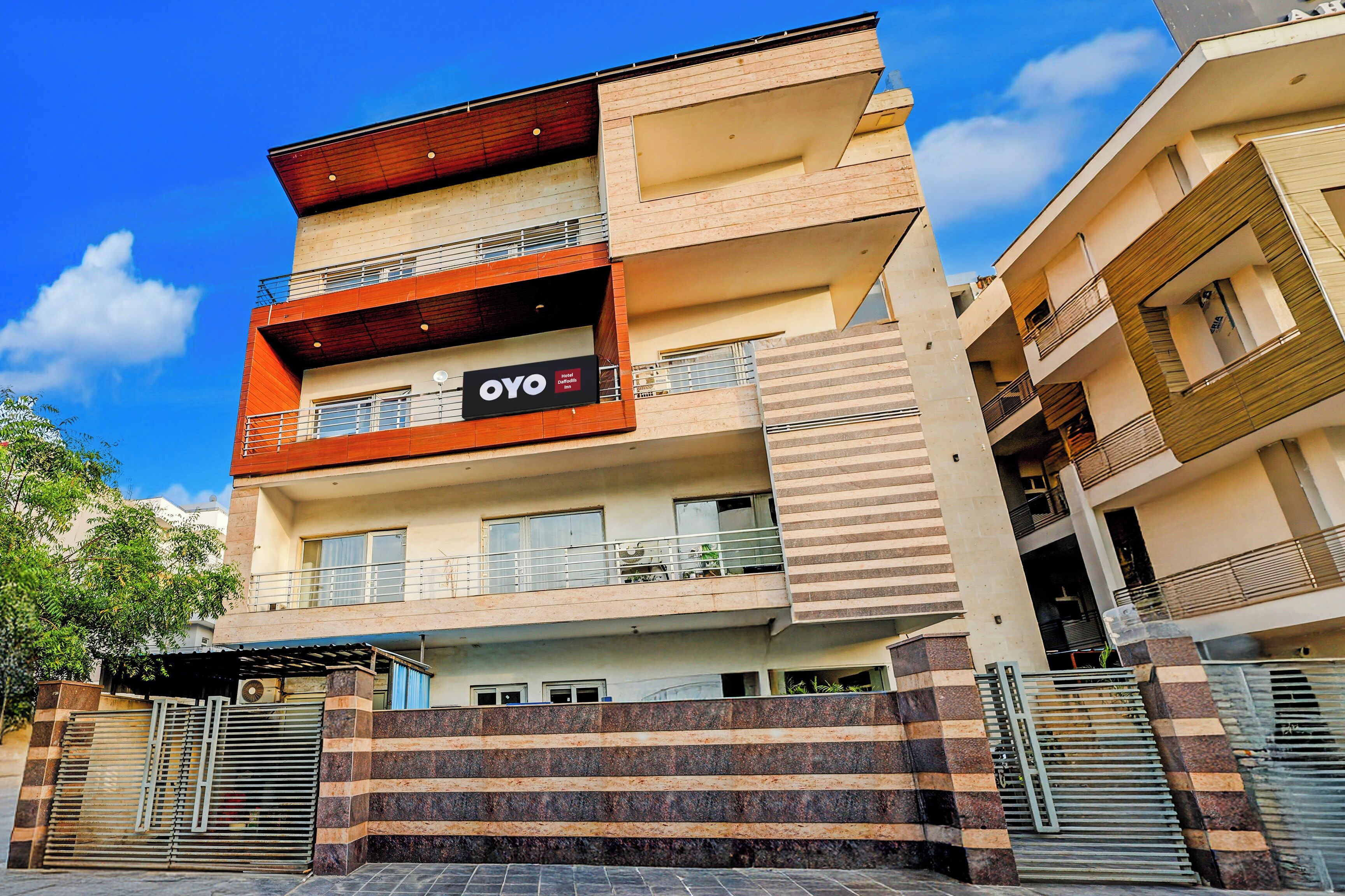 A multi-story hotel with balconies, a sign for 'OYO Hotel Daffodil Inn,' and a gated entrance.