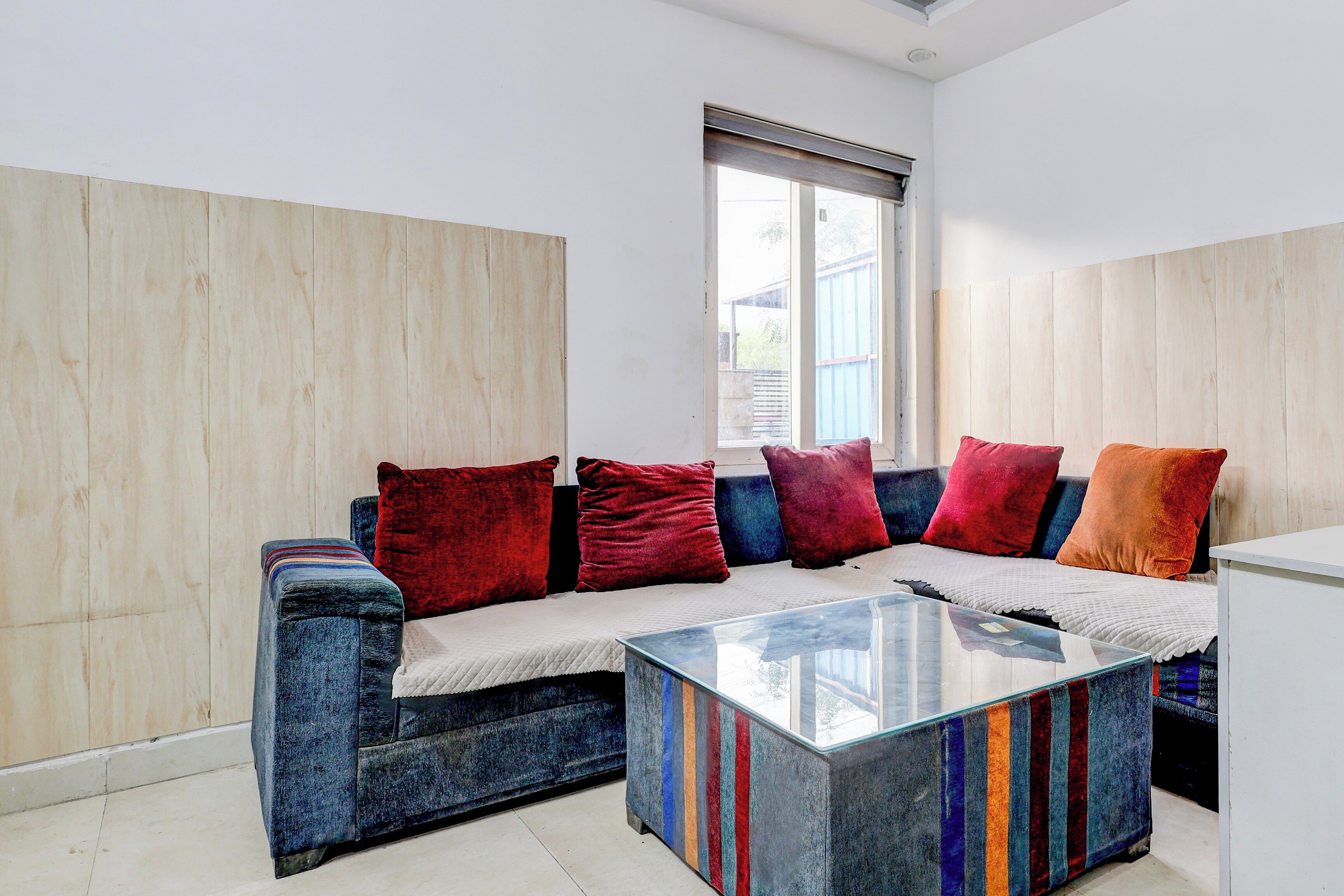 A modern living room with a sofa, colorful cushions, and a glass coffee table.
