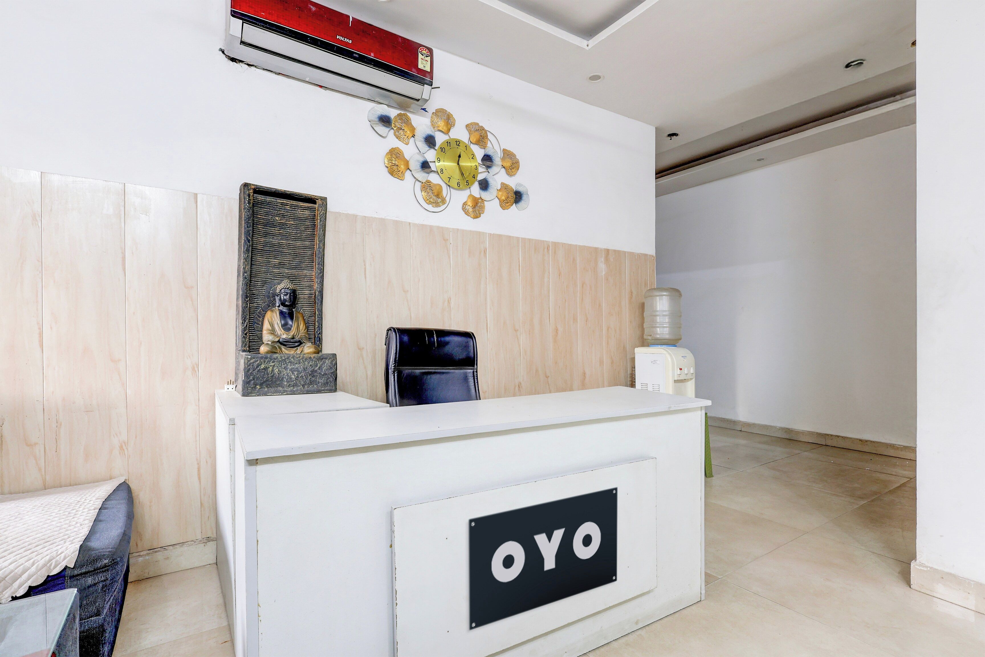A reception desk with a sign that reads 'OYO' and a clock above it.