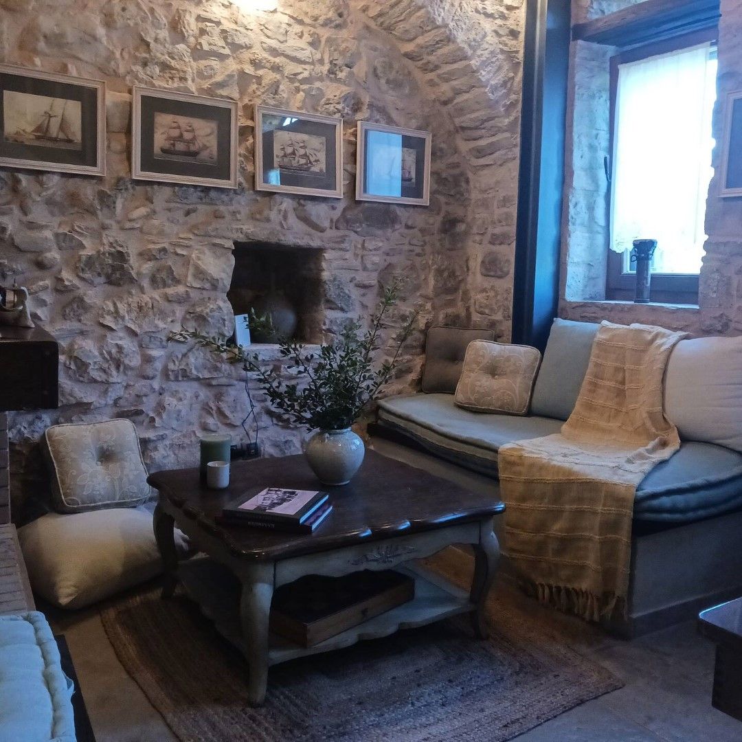 Habitació de parets de pedra amb un sofà, una taula de cafè i quadres a la paret.