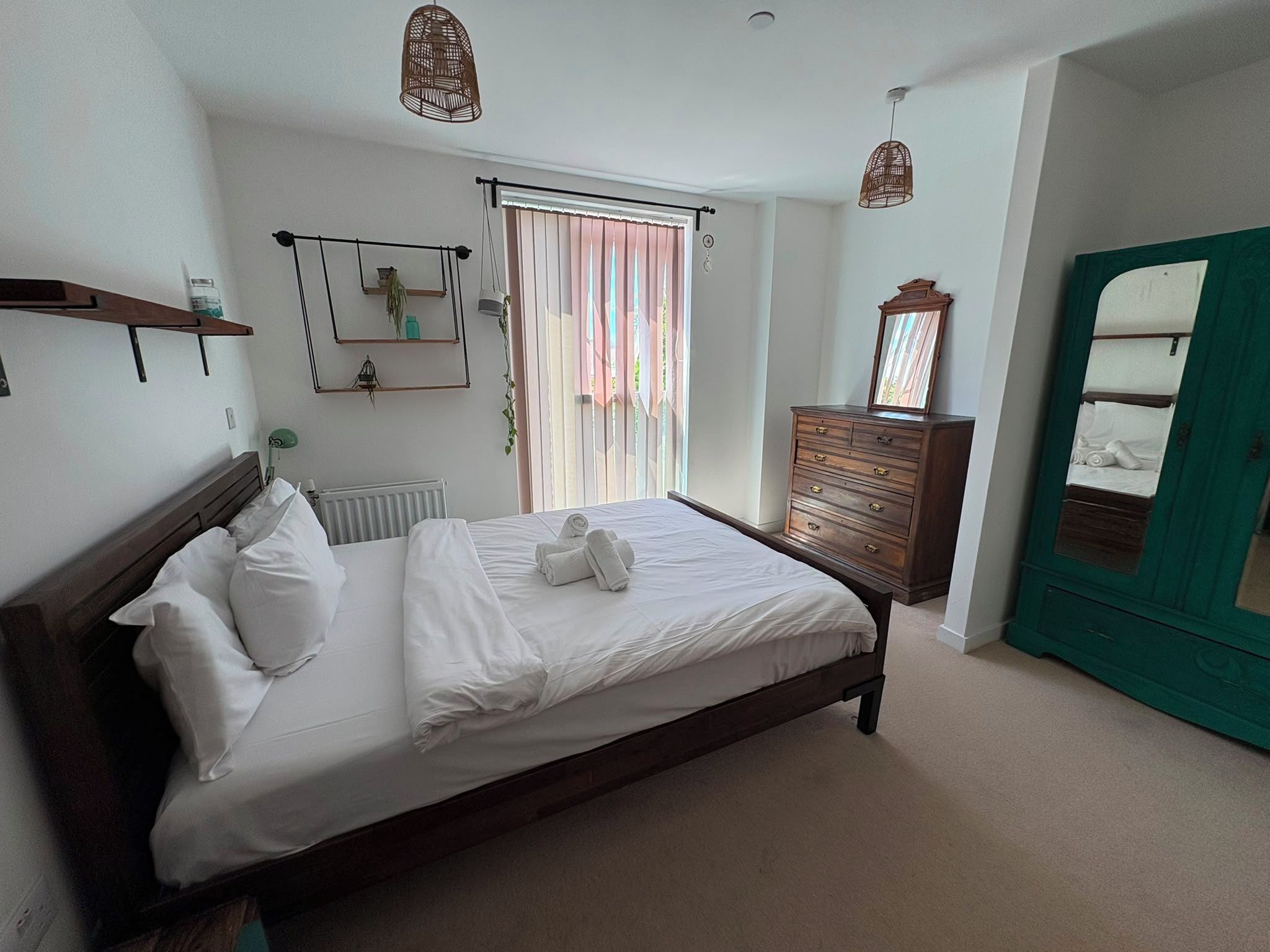 Une chambre à coucher avec un lit, une commode, un miroir et une fenêtre avec des rideaux.