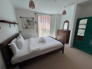 Un dormitorio con cama, cómoda, espejo y ventana con cortinas.