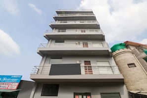 Un edificio de varios pisos con balcones y un gran cartel luminoso en la planta baja.