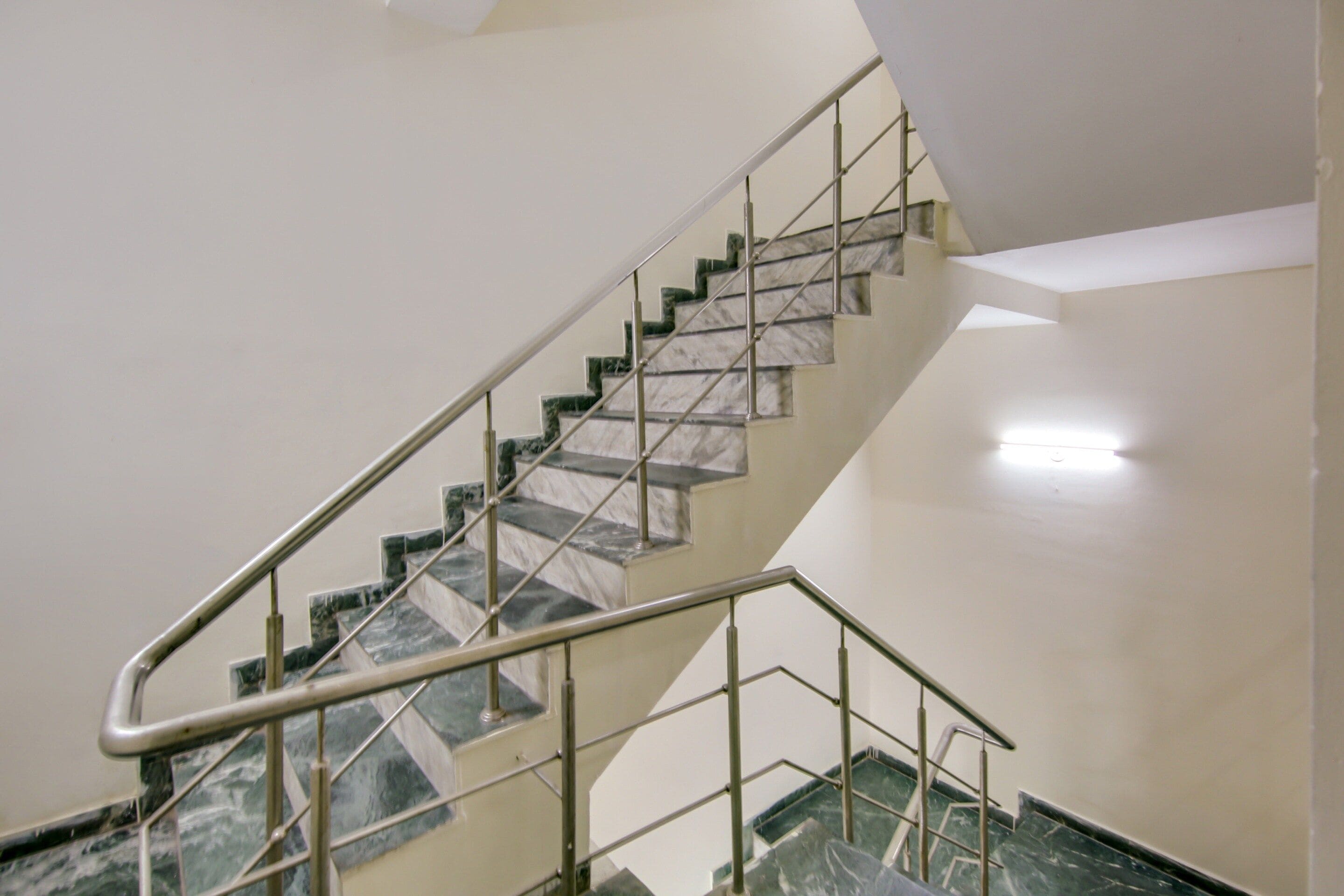Una escalera con escalones de mármol y barandillas de metal.