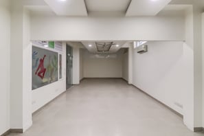 A hallway with a ceiling fan, recessed lighting, and a glass door on the left. - Hotel O Metro suites (Gurugram)