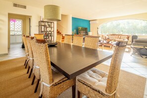 A dining area with a long table and wicker chairs, a hanging lamp, and a view of the outdoors. - New Listing (Forte dei Marmi)