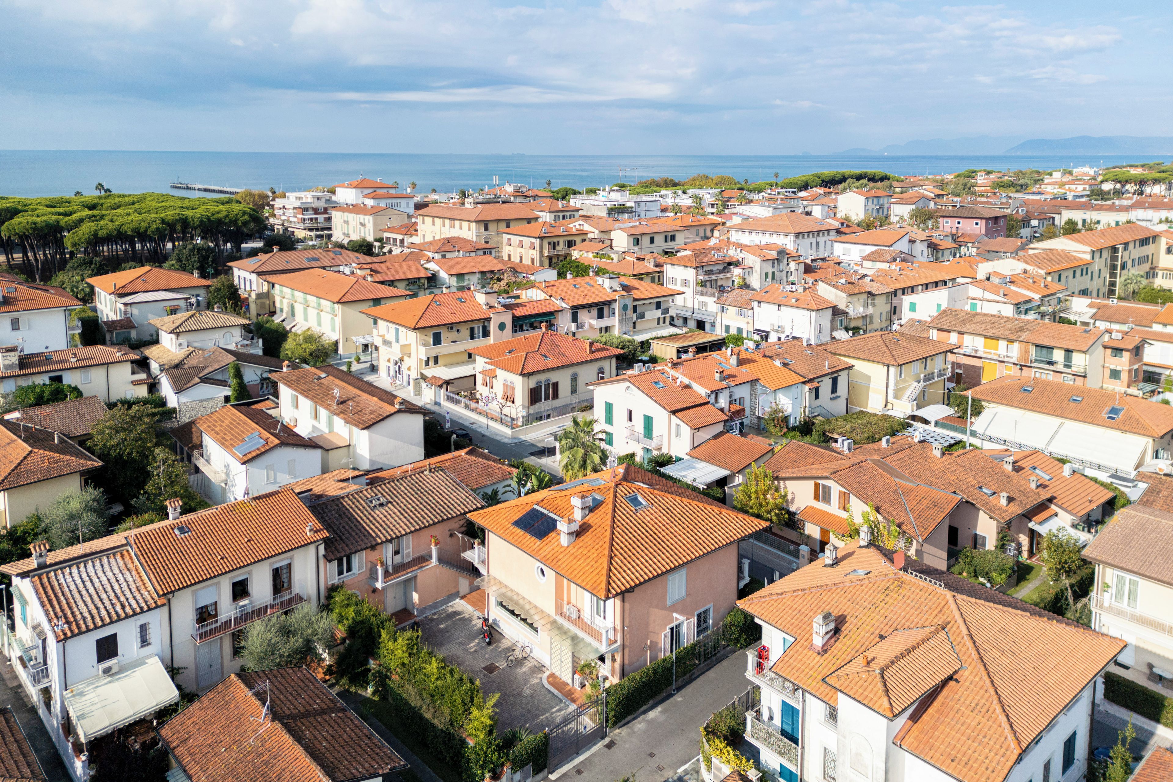 A coastal town with terracotta-roofed buildings, narrow streets, and a clear view of the sea.