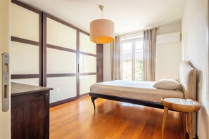 A bedroom with a bed, a bedside table, a lamp, a wardrobe, and a window with curtains. - New Listing (Forte dei Marmi)