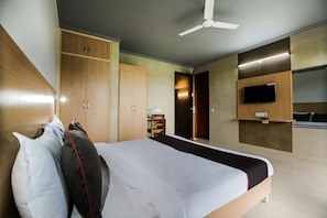 Et hotelværelse med seng, garderobeskab, fjernsyn og ventilator.