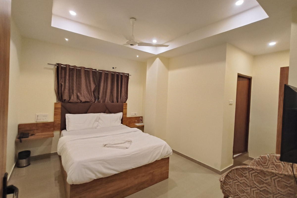 A bedroom with a bed, a ceiling fan, a nightstand, a chair, and a television.