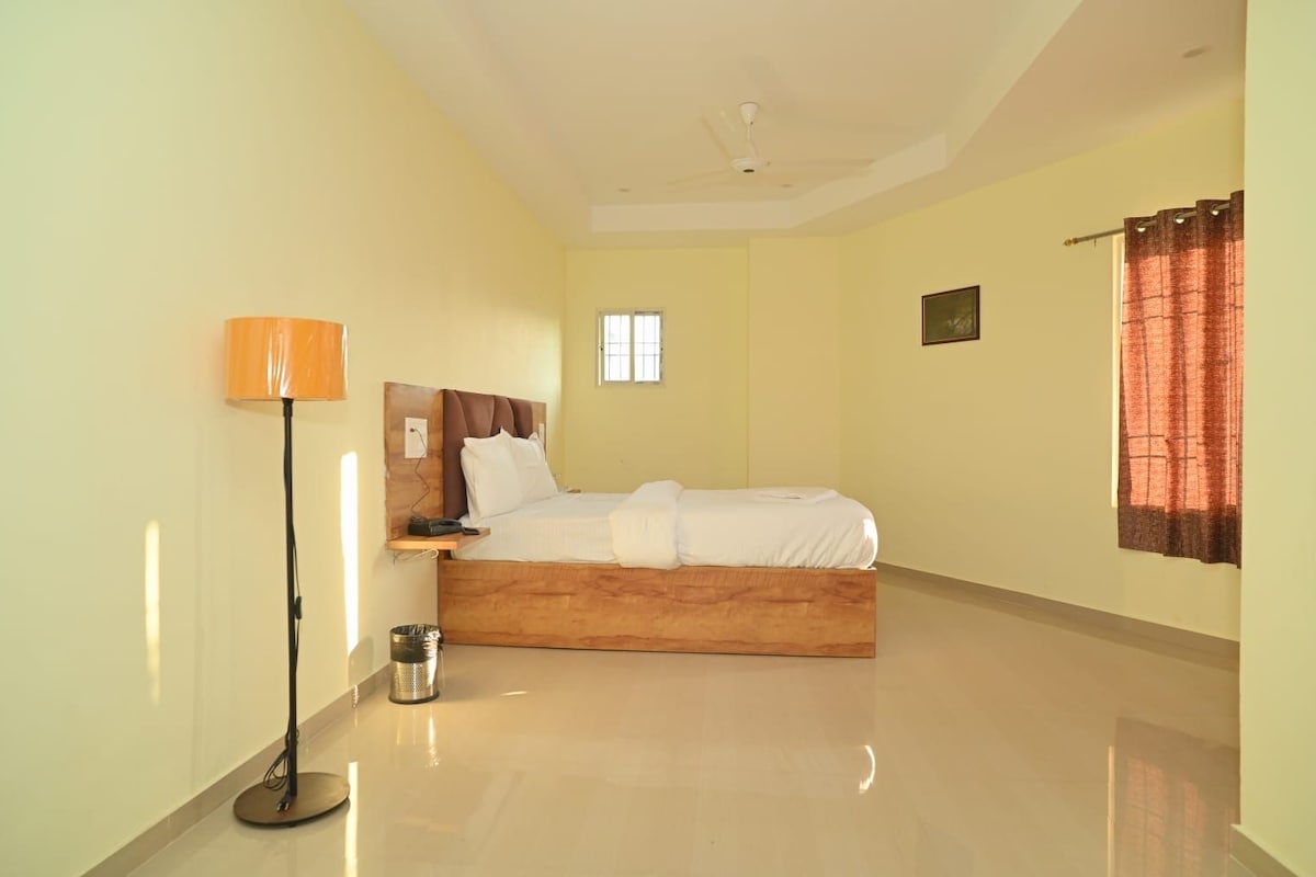 A bedroom with a bed, a bedside lamp, a window, and a curtain.