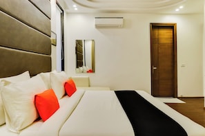 A hotel room with a bed, a bedside table, a mirror, and a door. - Hotel O Pink Stays (Gurugram)