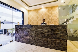 A reception desk with a patterned wall and a marble floor. - Hotel O Pink Stays (Gurugram)
