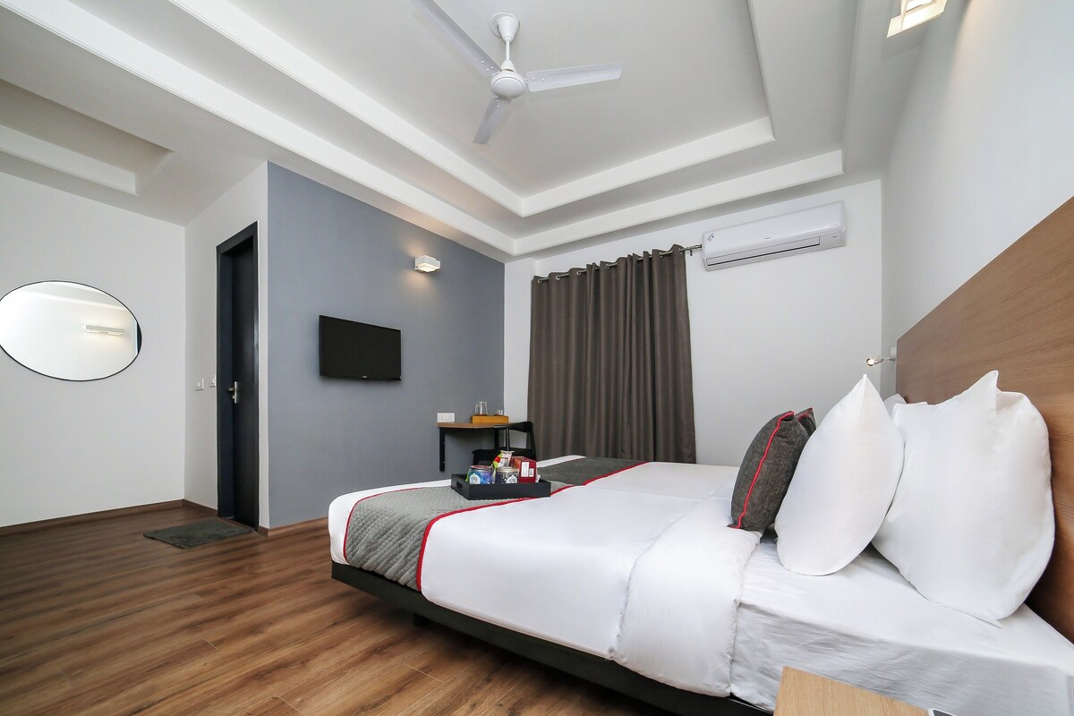 A hotel room with a bed, a flat-screen TV, a ceiling fan, and an air conditioning unit.
