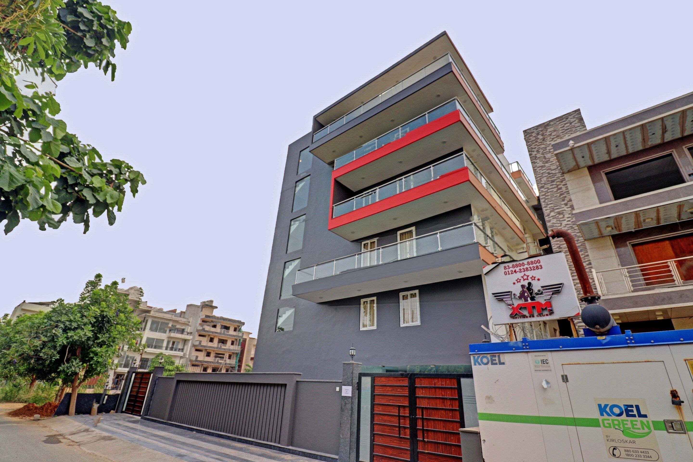 A multi-story building with balconies, a gated entrance, and signage for a fitness club.