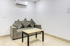 Et værelse med en grå sofa, et træbord og en hvid aircondition på væggen.