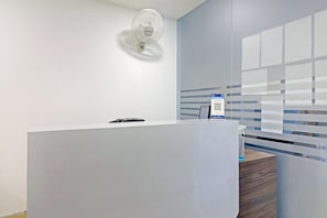 En moderne receptionsdisk, vægmonteret ventilator og en QR-kode til digitale tjenester.