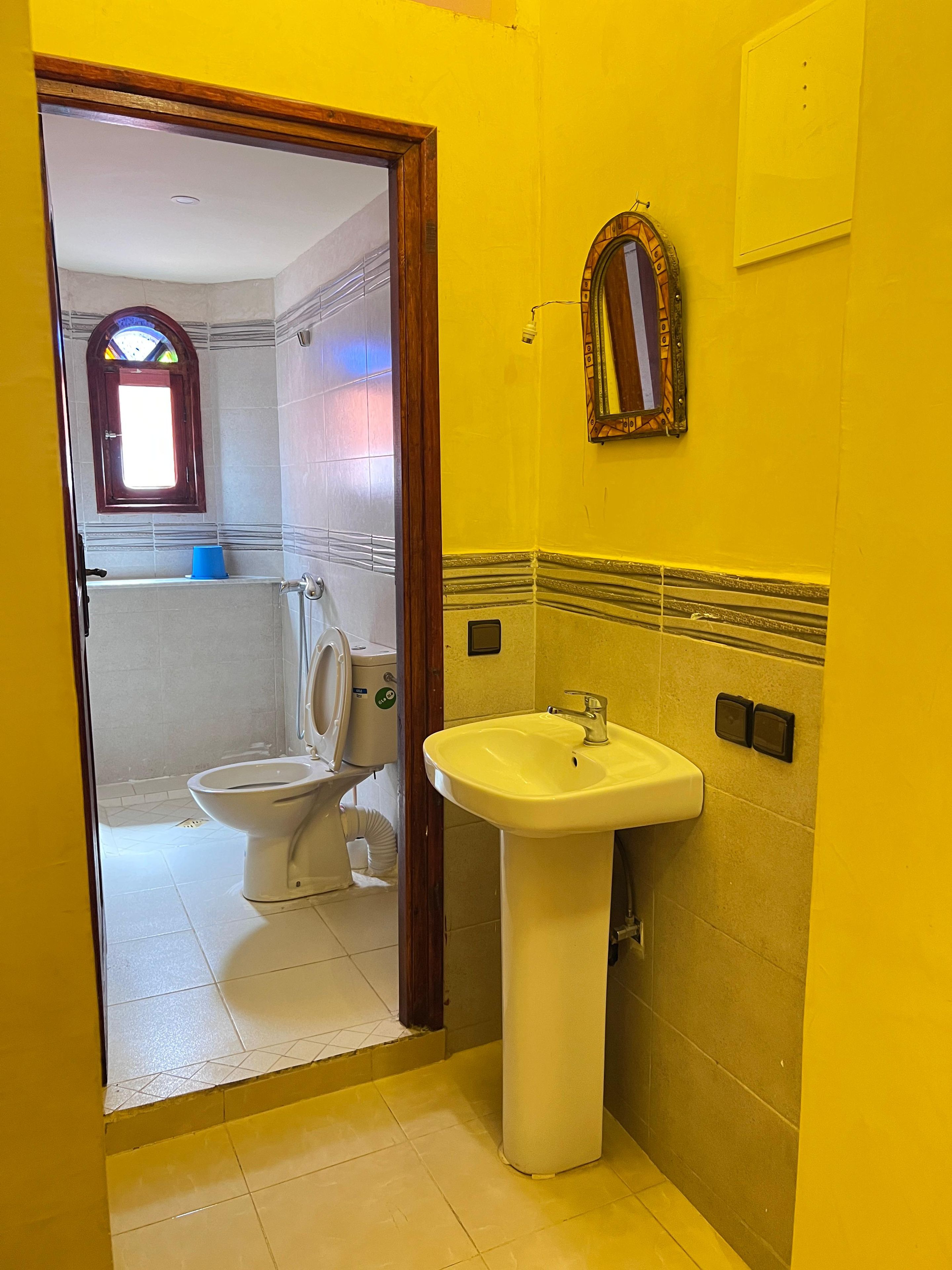 A bathroom with a yellow wall, a white sink, and a toilet.