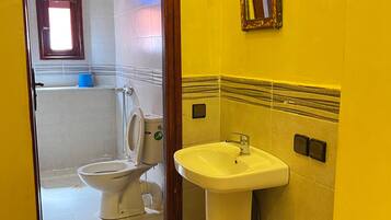 A bathroom with a yellow wall, a white sink, and a toilet.