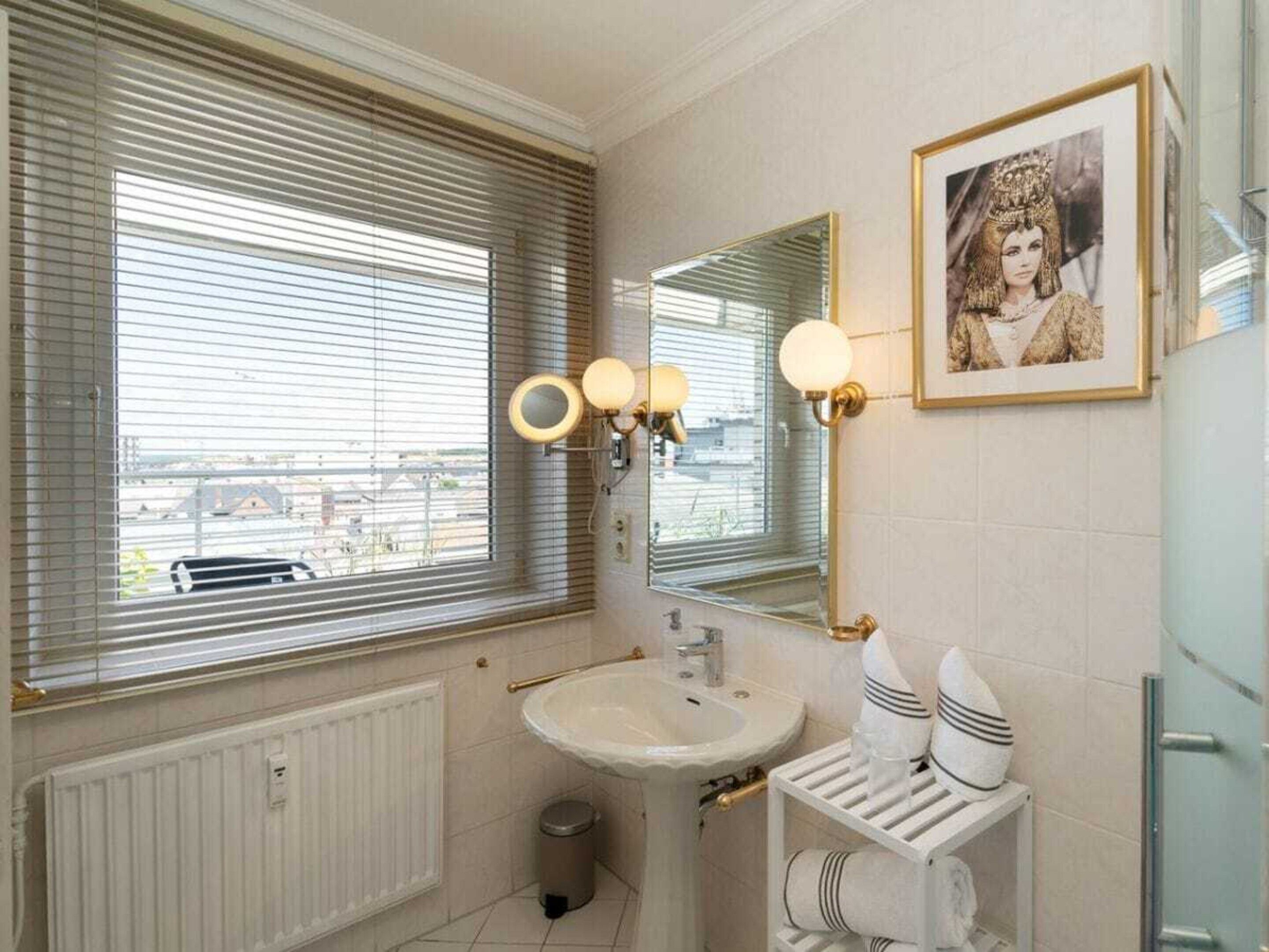A bathroom with a sink, mirror, and window blinds.