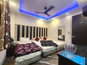 A modern bedroom with two beds, a ceiling fan, and a large mirror. - Oly Hotel Shiva Inn (New Delhi)