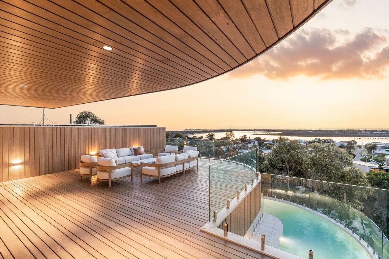 A modern outdoor deck with a pool, wooden flooring, and seating area.