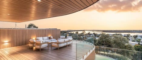 A modern outdoor deck with a pool, wooden flooring, and seating area.