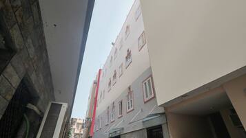 Une rue étroite bordée de bâtiments des deux côtés, où se côtoient des immeubles d’habitation et des locaux commerciaux.