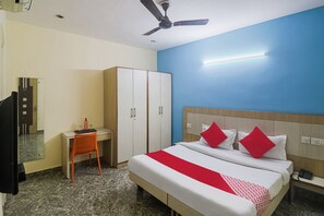 Une chambre d’hôtel équipée d’un lit, d’un bureau, d’une armoire et d’un ventilateur de plafond.