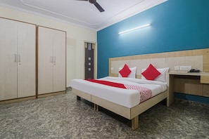Une chambre d’hôtel équipée d’un lit, d’une armoire, d’un bureau et d’un ventilateur de plafond.