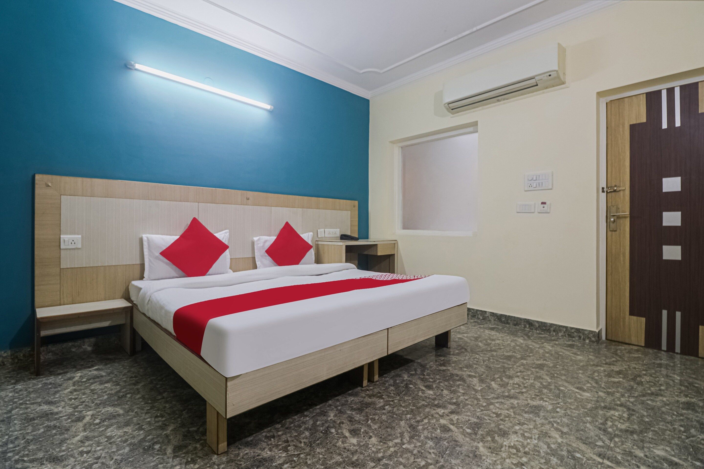 Une chambre d’hôtel avec un lit, des tables de chevet, une armoire et une porte.