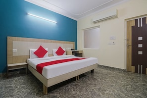 Une chambre d’hôtel avec un lit, des tables de chevet, une armoire et une porte.