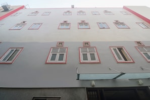 Ein mehrgeschossiges Gebäude mit flachem Dach und zahlreichen Fenstern mit roten Rahmen.