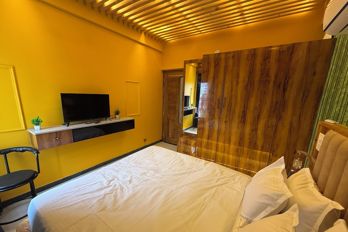 Une chambre d’hôtel avec un lit, un téléviseur posé sur une étagère, une chaise et une armoire.