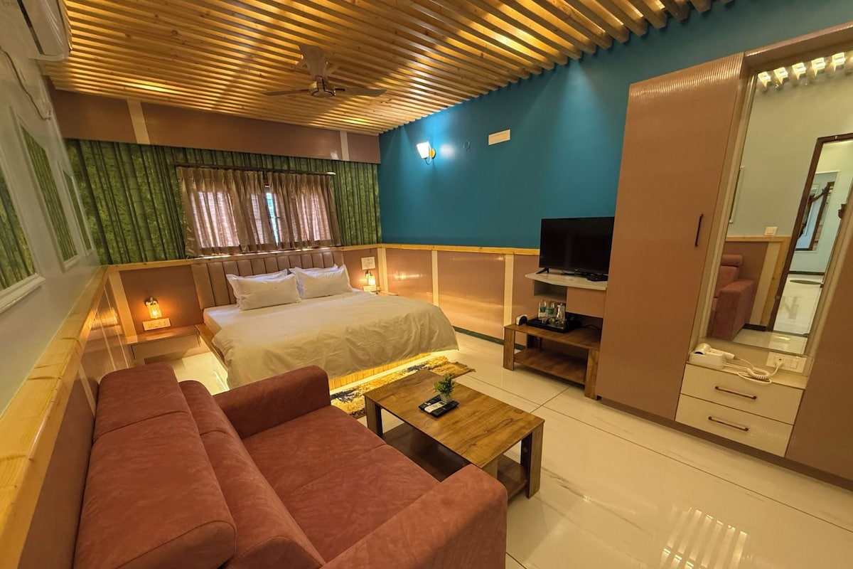 Une chambre d’hôtel comprenant un lit, un canapé, une télévision, une armoire et un miroir.